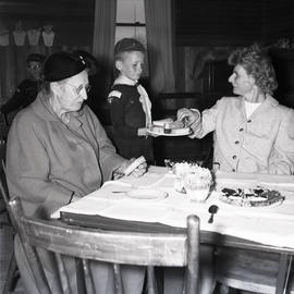 Uniformed boy serving tea to women