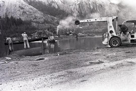 Men and truck doing something by water